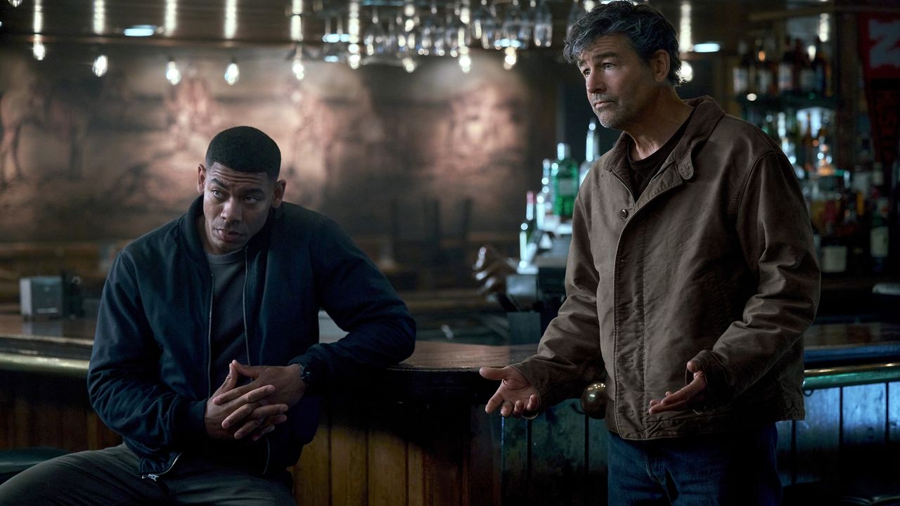 Cena de Lanterns: dois homens conversam num bar mal iluminado, num plano de tom escuro